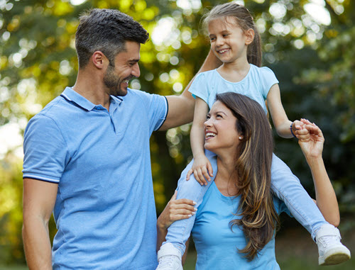 A husband and wife walking outdoors with their daughter, reconnected after resolving a conflict in their marriage.